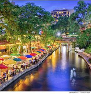 a river with colorful umbrellas and people sitting at tables at 1 Story-4BR/5Beds/2.5BA Lackland-Missions-Downtown in San Antonio