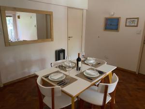 - une table à manger avec des chaises blanches et une bouteille de vin dans l'établissement Cómodo departamento en el centro de Mendoza, à Mendoza