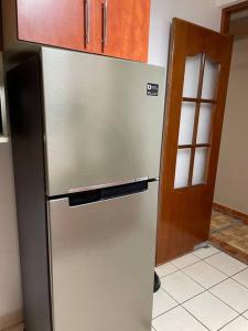 a stainless steel refrigerator in a kitchen next to a door at Apartamento a 10 min del centro de la ciudad in Huaraz
