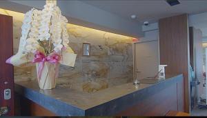 a vase of flowers on a counter in a lobby at HOTEL GrayⅡ in Osaka