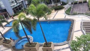 uma piscina com palmeiras num pátio em Del's Condotel em Manila