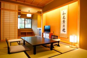 a room with a table and chairs and a television at Kyoto Arashiyama Onsen Ryokan Togetsutei in Kyoto
