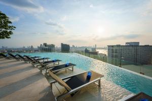 a pool on the roof of a building with chairs at Somerset Pattaya - SHA Plus in Pattaya Central