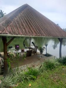 een prieel met een tafel en stoelen naast een meer bij Orchid Island B&B on the River with Pool & Jetty in Pacific Harbour