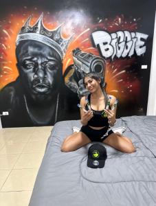 una mujer sentada en una cama delante de un cartel en The Green Spot en Pattaya centro