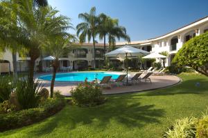 a resort with a swimming pool with chairs and umbrellas at Hotel Guadalajara Plaza Ejecutivo in Guadalajara