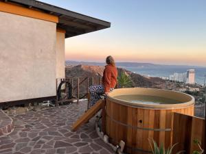 a woman standing on a balcony with a hot tub at Native Residence in Rosarito