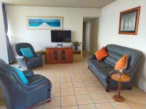 a living room with two chairs and a couch and a tv at Ebbtide 26 in Forster