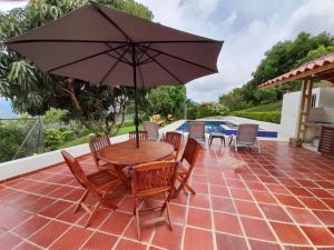 a wooden table and chairs with an umbrella on a patio at FINCA LUNADAR ANAPOIMA in Anapoima