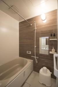 une salle de bain avec une baignoire, des toilettes et un lavabo dans l'établissement ゲストハウス京都ミルズ紅藤庵, à Kyoto