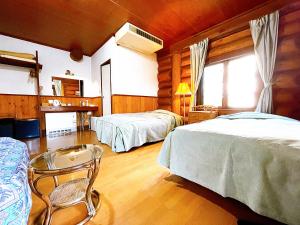 a bedroom with two beds and a chair in it at Hakuba Pension & Log Hotel Meteor in Hakuba