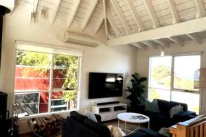 a living room with a couch and a flat screen tv at Apollo Bay Rocket House l Pet-Friendly Free Wi-Fi in Apollo Bay
