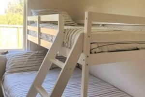 two bunk beds in a room with a window at Apollo Bay Rocket House l Pet-Friendly Free Wi-Fi in Apollo Bay