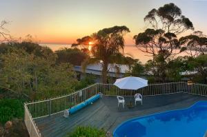 a swimming pool with an umbrella and two chairs at The River Suites, Kangaroo Island in American River