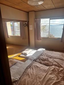 a bed in a room with two windows at ペンションレークサイド in Otsu