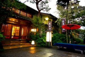 a building with a red umbrella and a blue bench at Kyoto Arashiyama Onsen Ryokan Togetsutei in Kyoto