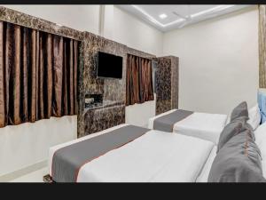 a bedroom with two beds and a tv on the wall at Hotel Bhavya Residency in Jāmb