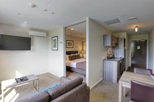 a living room with a couch and a bedroom at Ramada Suites by Wyndham Queenstown Remarkables Park in Queenstown