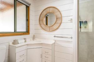 une salle de bain blanche avec un lavabo et un miroir dans l'établissement The Beach Cottage, à Wye River 5 autres photos