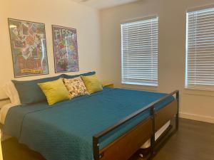 a bedroom with a bed with blue sheets and two windows at Alamo City Haven in San Antonio