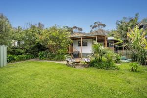 une maison avec une cour avec un banc dans l'établissement The Beach Cottage, à Wye River