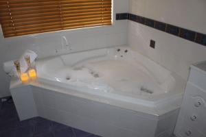 La salle de bains est pourvue d'une baignoire blanche avec bougie. dans l'établissement Granite Gardens Cottages & Lake Retreat, à Stanthorpe 23 autres photos