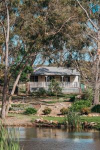 une maison assise sur le bord d'une rivière dans l'établissement Granite Gardens Cottages & Lake Retreat, à Stanthorpe