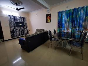 ein Wohnzimmer mit einem Tisch, Stühlen und einem Gemälde in der Unterkunft J2 Home Stay - Luxury Homes with Caravan Services in Thiruvananthapuram