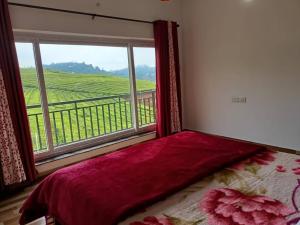 a bed in a room with a window with a view at Tea Estate view stay in Ooty