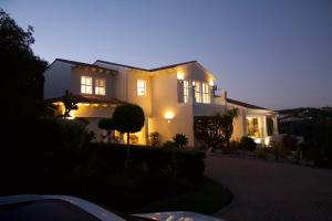 Plett Luxury Home في بليتنبيرغ باي: منزل أبيض في الليل مع إضاءته