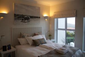 Plett Luxury Home في بليتنبيرغ باي: غرفة نوم بسرير أبيض ونافذة +4 صور