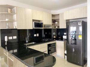 a kitchen with a stainless steel refrigerator and black counter tops at Bocagrande Infinitum Vista mar Gym Coworking in Cartagena de Indias +12 photos