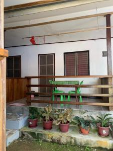 un porche con un banco verde y macetas en Bundal Riverside Room#2 with Balcony or Terrace en San Vicente