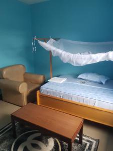 a bedroom with a bed and a chair and a table at Cozy Master bedroom with Free Wi-Fi in Tanga in Tanga