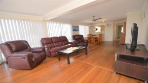 sala de estar con muebles de cuero y TV de pantalla plana en 1 5 Pilot Street Yamba, en Yamba