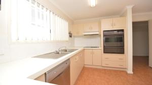 Una cocina con gabinetes blancos y un fregadero y una ventana. en 1 5 Pilot Street Yamba, en Yamba
