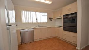 a kitchen with white cabinets and a sink and a window at 1 5 Pilot Street Yamba in Yamba