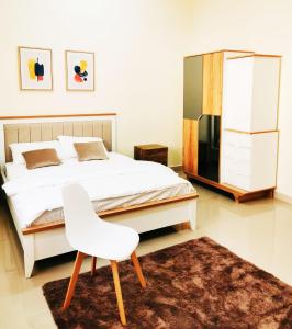 um quarto com uma cama branca e uma cadeira branca em Abu Rakan Apartment em Mascate