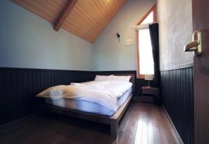 Goodfellas Onsen House في نيسيكو: غرفة نوم مع سرير في غرفة مع نافذة