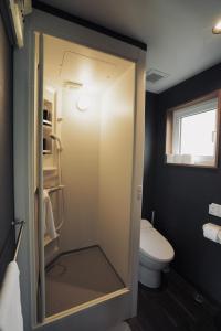 a bathroom with a toilet and a glass shower door at Goodfellas Onsen House in Niseko