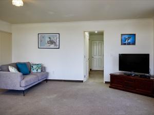 a living room with a couch and a flat screen tv at Torquay Central - Kaikoura Holiday Home in Kaikoura