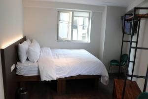 um quarto com uma cama com lençóis brancos e uma janela em H HOSTEL Itaewon em Seul