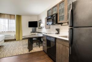 a kitchen with a refrigerator and a table in a room at Candlewood Suites Portland Airport, an IHG Hotel in Portland