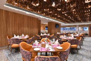 a restaurant with tables and chairs in a room at Regenta Fairlark Vadodara in Vadodara