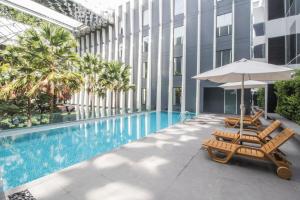 une piscine avec deux chaises longues et un parasol dans l'établissement Bangkok Midtown Hotel, à Bangkok