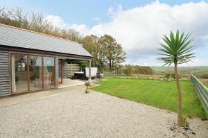 a house with a palm tree next to a yard at Pol Glas Cabin in Helston