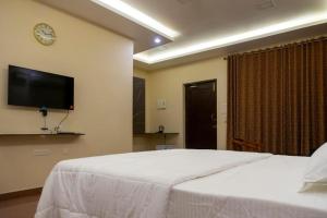 a bedroom with a white bed and a tv on the wall at Pranaav Beach Resort in Puducherry +4 photos