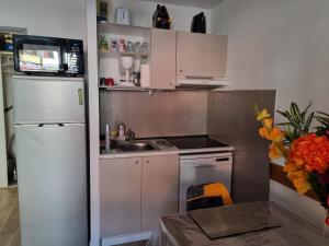 una pequeña cocina con armarios blancos y nevera. en Agréable appartement de 6 pers au pieds des pistes ,wifi gratuit à Saint-Sorlin-d'Arves labelise 3 étoiles au gîte de France en Saint-Sorlin-dʼArves