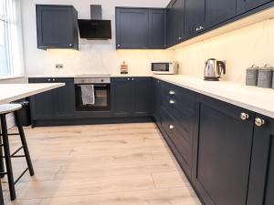 uma cozinha com armários pretos e piso em madeira em 37 Nutter Road em Cleveleys