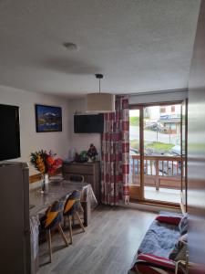 a living room with a dining table and a balcony at Agréable appartement de 6 pers au pieds des pistes ,wifi gratuit à Saint-Sorlin-d'Arves labelise 3 étoiles au gîte de France in Saint-Sorlin-dʼArves